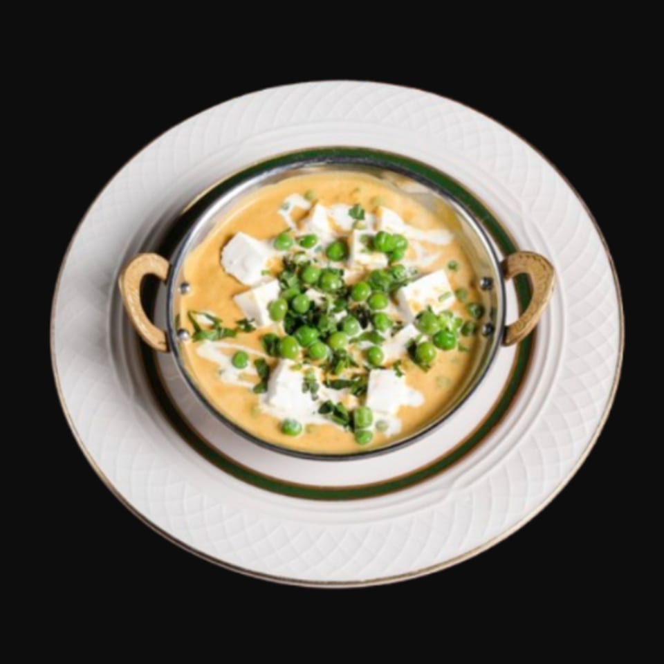 Mutter Paneer, an Indian dish with peas and paneer cheese in a creamy orange sauce, served in a metal bowl.