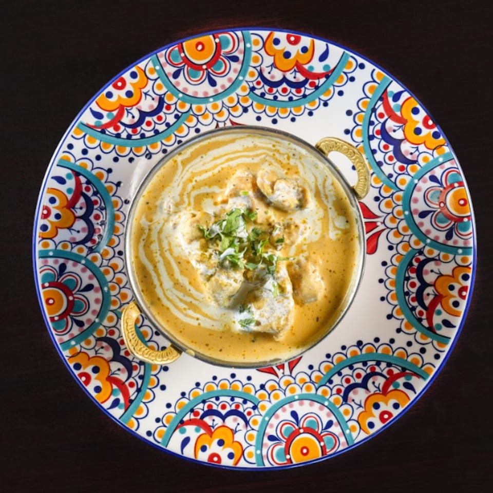 Kalia Indian Cuisine's creamy chicken curry in a decorative bowl with cilantro garnish.