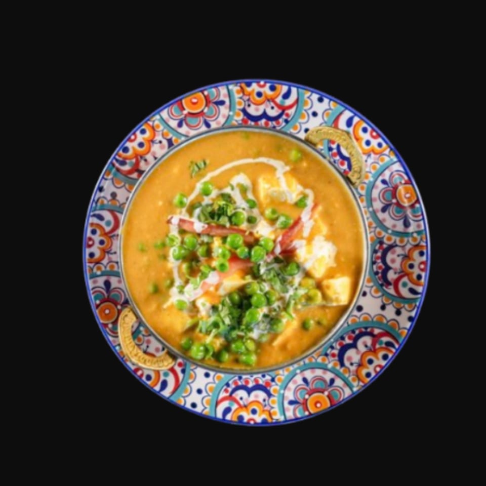 Mutter Paneer, an Indian dish with peas and cheese in a creamy orange sauce, served in a colorful bowl.
